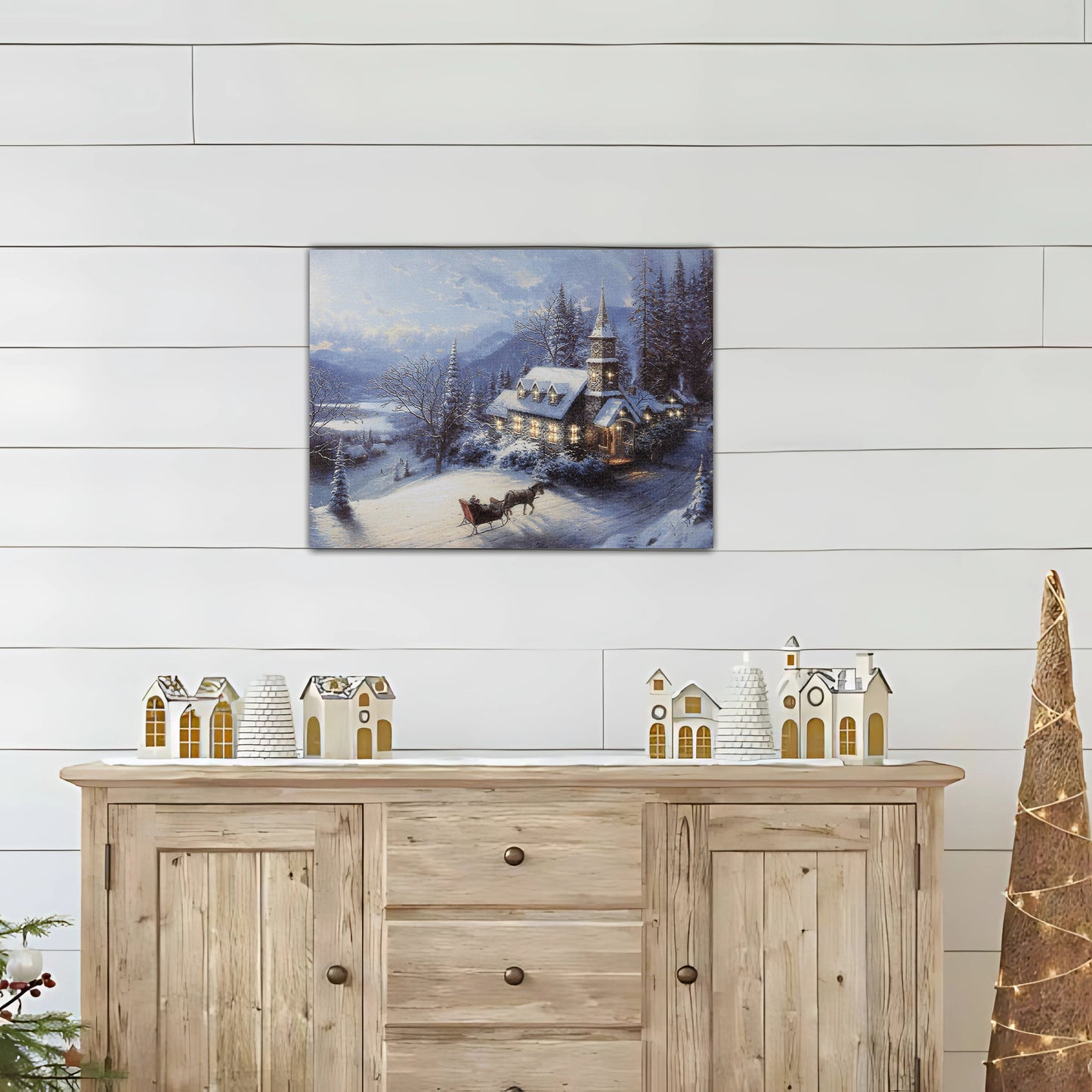 Canvas winter landscape print above a wooden sideboard with decorative items.