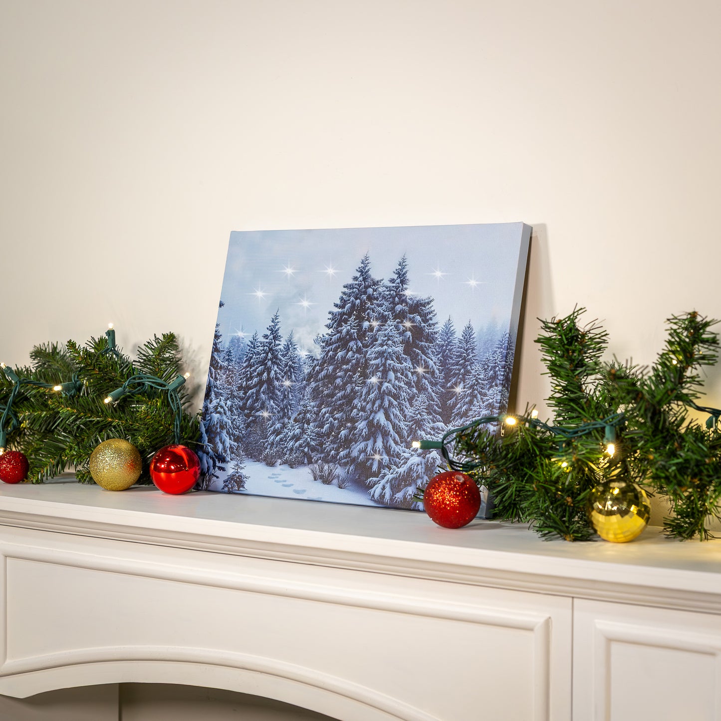 Canvas print of a snowy forest scene on a mantelpiece with Christmas decorations.