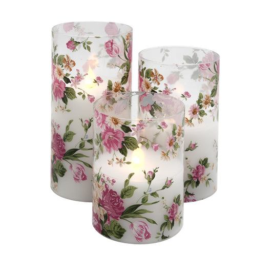 Set of three battery operated clear glass hurricane candles with a floral design, featuring a wax candle inside and an LED light visible through the glass.
