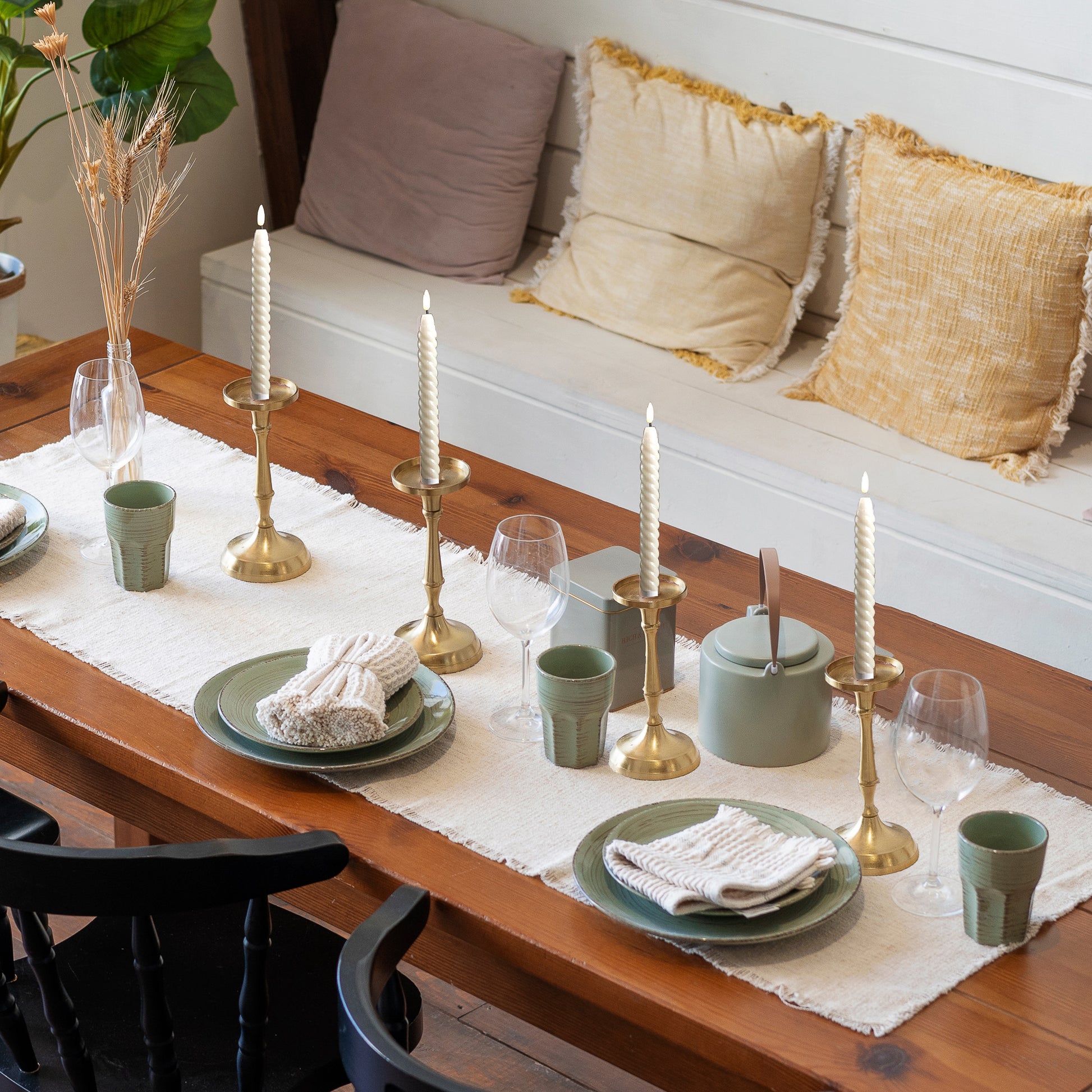 Set of four battery operated  flameless twisted wax taper candles with 3D wick in candleholders on table set for three.