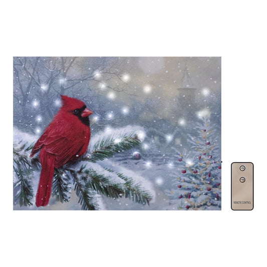 A battery operated lighted wall art featuring a vibrant print of a red cardinal bird perched on a pine tree branch with a wintry scene in the background including snow on the ground and a Christmas tree.