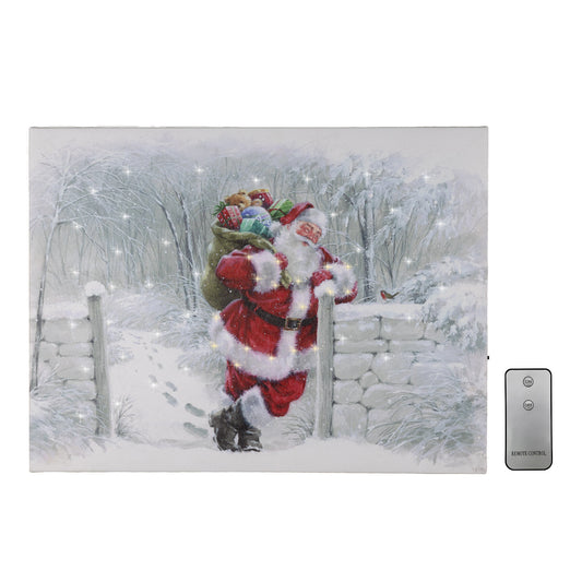 A canvas print depicting Santa Claus in a snowy field, with a remote control next to it.