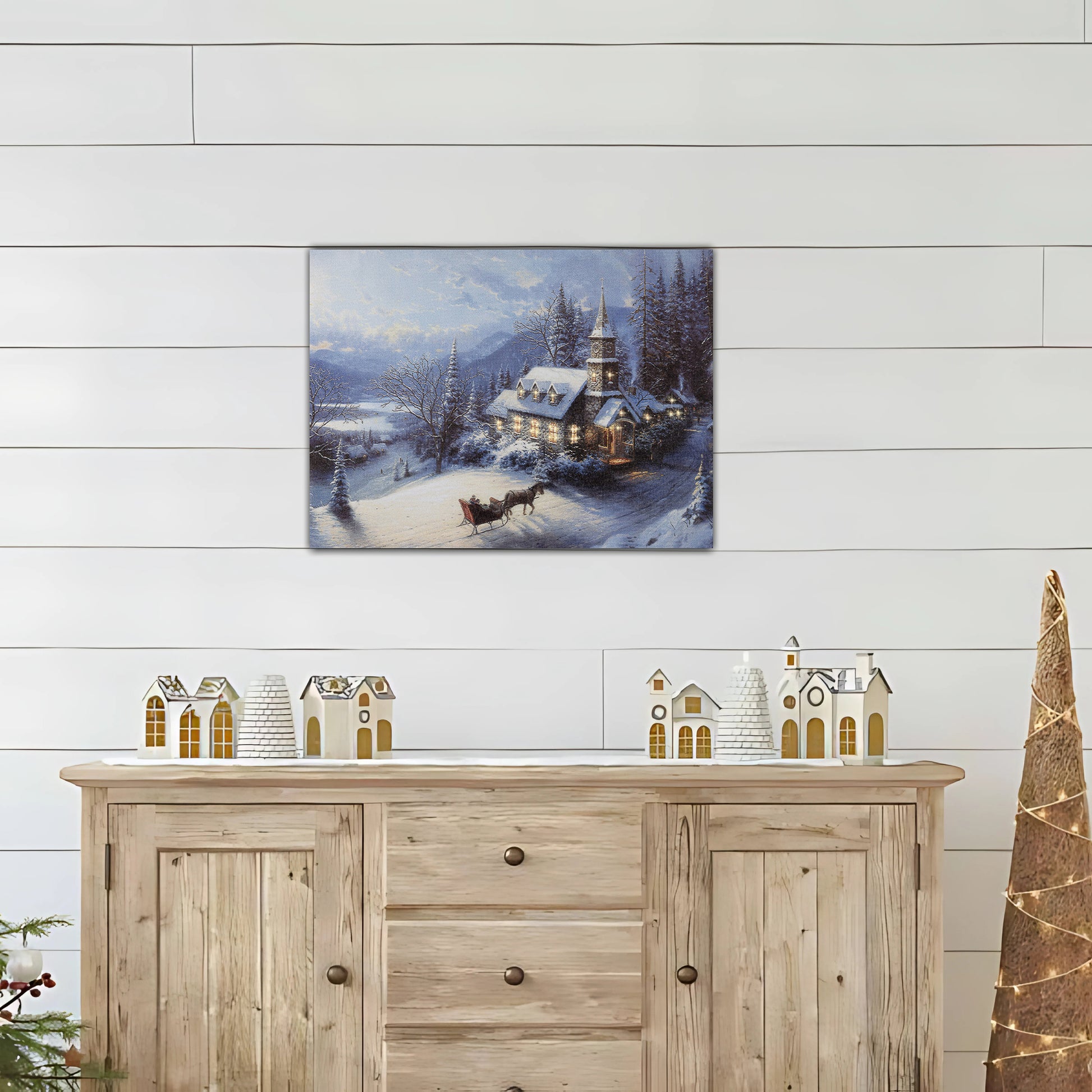 Canvas winter landscape print above a wooden sideboard with decorative items.
