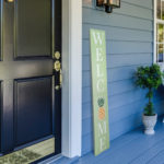 Green welcome sign on porch next to front door