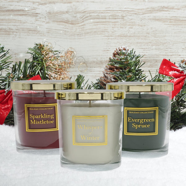 Christmas scented candles, set of 3, in snow surrounded by holiday garland.