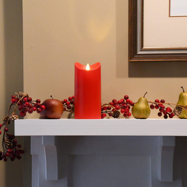 Red pillar candle on fireplace mantel